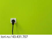 White plastic power outlet. Power socket. Brand new electrical socket isolated on a lime green wall, black single plug switched on. Renovated studio apartment power supply background. Empty copy space. Стоковое AI-изображение, AI-художник Марина Демидюк / Фотобанк Лори