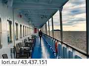 Deck of a ship, lake view, north sea from aboard a cruise ship. Unrecognizable silhouette of a walking and resting woman. The theme of traveling in northern regions and cold water spaces. Стоковое фото, фотограф Оксана Медведева / Фотобанк Лори