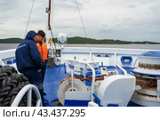 Karelia, Russia, July 21, 2023. Deck of the ship Symphony of the North, sailors preparing to dock the ship. The theme of traveling in northern regions and cold water spaces. Редакционное фото, фотограф Оксана Медведева / Фотобанк Лори