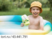It's a hot day. A cute boy is swimming and splashing in the pool. A happy little boy smiles at the camera. Splashes of water are flying in all directions. The concept of summer holidays with children. Стоковое фото, фотограф Photojuli / Фотобанк Лори
