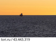 Красивый вечерний морской пейзаж. Вид на грузовое судно в море на закате. Морские контейнерные перевозки. Минималистский пейзаж. Отлично подходит для фона. Стоковое фото, фотограф Андрей Степанов / Фотобанк Лори