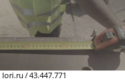 Строитель в жилетке измеряет рулеткой железную конструкцию a builder in a vest measures an iron structure with a tape measure. Стоковое видео, видеограф Опока Алексей / Фотобанк Лори