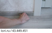 The master finisher installs a plastic baseboard, snapping it into the grooves. Home renovation. Стоковое видео, видеограф Дмитрий Кобзев / Фотобанк Лори