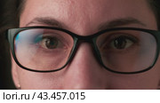 Close-up of a young adult Caucasian brunette woman looking at the camera and putting on glasses. Ophthalmology and vision impairment concept. Стоковое видео, видеограф Денис Кебедов / Фотобанк Лори