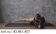 A middle-aged athletic woman performs myofascial massage of the leg muscles, rolls the muscles of the inner thigh with a special massage roller, trains in a room near the wall. Стоковое видео, видеограф Сергей Чайко / Фотобанк Лори