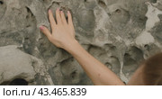 A close-up of a hand touching the textured surface of a weathered rock at the Bastei rock formations in Germany. Стоковое видео, видеограф Igor Tichonow / Фотобанк Лори