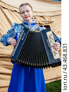 Moscow, Russia, October 1, 2016: Cossack gathering A Cossack girl demonstrates virtuoso harmonica playing. A girl with a musical instrument in her hands. Harmonica is the national Russian instrument. Редакционное фото, фотограф Оксана Медведева / Фотобанк Лори