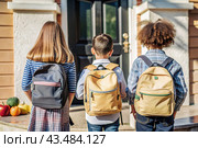 The holiday falls on September 1st. Children with yellow backpacks run to school. Rear view. Back to school. The concept of a new academic year at school. Autumn Knowledge Day. Стоковое AI-изображение, AI-художник Photojuli / Фотобанк Лори