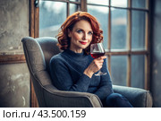 Close-up. A modern, stylish, beautiful woman with red hair and a glass of red wine in an armchair in the living room of the house. Стоковое AI-изображение, AI-художник Photojuli / Фотобанк Лори