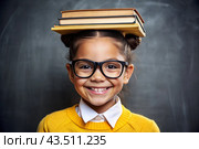 A pretty girl with glasses and books on her head. The child goes to school for the first time. A child in the classroom on the background of a blackboard. Back to school. Стоковое AI-изображение, AI-художник Photojuli / Фотобанк Лори