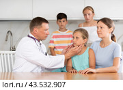Man doctor examines throat and lymph nodes of small girl patient at home. Стоковое фото, фотограф Яков Филимонов / Фотобанк Лори