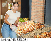 While shopping at shop, girl got rotten potato and she grimaces at unpleasant smell of spoiled item. Стоковое фото, фотограф Яков Филимонов / Фотобанк Лори