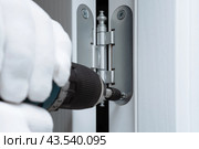 Установка межкомнатной двери и прикручивание дверной петли шуруповертом. Стоковое фото, фотограф Viktoriya S. / Фотобанк Лори