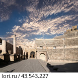 Roman Theatre in Amman, Jordan -- theatre was built the reign of Antonius Pius (138-161 CE), the large and steeply raked structure could seat about 6000 people. Against the sky with clouds (2016 год). Стоковое фото, фотограф Владимир Журавлев / Фотобанк Лори