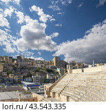 Roman Theatre in Amman, Jordan -- theatre was built the reign of Antonius Pius (138-161 CE), the large and steeply raked structure could seat about 6000 people. Against the sky with clouds (2016 год). Стоковое фото, фотограф Владимир Журавлев / Фотобанк Лори
