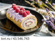Swiss sponge roll with raspberries, a delicious fruit and cream dessert filled with cream cheese, decorated with fresh raspberries. Стоковое AI-изображение, AI-художник Photojuli / Фотобанк Лори