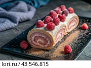 Swiss sponge roll with raspberries, a delicious fruit and cream dessert filled with cream cheese, decorated with fresh raspberries. Стоковое AI-изображение, AI-художник Photojuli / Фотобанк Лори