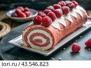 Swiss sponge roll with raspberries, a delicious fruit and cream dessert filled with cream cheese, decorated with fresh raspberries. Стоковое AI-изображение, AI-художник Photojuli / Фотобанк Лори