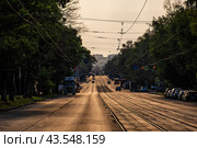 Улица города с трамвайными путями ранним утром, залитая золотым светом Солнца (2024 год). Редакционное фото, фотограф Илья Старков / Фотобанк Лори