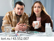 Woman and man wrapped in plaids having symptoms of cold at home. Стоковое фото, фотограф Яков Филимонов / Фотобанк Лори