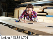 Sad and confused female employee examines defects on wooden board. Стоковое фото, фотограф Яков Филимонов / Фотобанк Лори