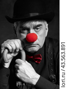Dramatic selective color portrait of a clown against a dark background leaning on the handle of an umbrella. Стоковое фото, фотограф Сергей Пристяжнюк (Serg Zastavkin) / Фотобанк Лори