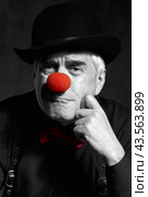 Dramatic selective color portrait of a sad clown against a dark background. Hand near face. Стоковое фото, фотограф Сергей Пристяжнюк (Serg Zastavkin) / Фотобанк Лори