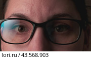 Close-up of a young adult Caucasian brunette woman looking at the camera and putting on glasses. Ophthalmology and vision impairment concept. Стоковое видео, видеограф Денис Кебедов / Фотобанк Лори