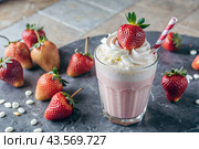 Refreshing strawberry milkshake with whipped cream and a straw on the table surrounded by fresh strawberries. Стоковое AI-изображение, AI-художник Photojuli / Фотобанк Лори