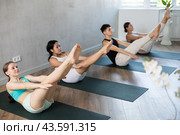 Girl performs boat asana - Paripurna navasana in group class. Стоковое фото, фотограф Яков Филимонов / Фотобанк Лори