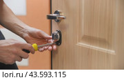 Installation and replacement of door locks. Door repair. A locksmith installs door hardware by tightening a screw with a screwdriver. Стоковое видео, видеограф Дмитрий Кобзев / Фотобанк Лори