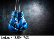 Professional blue boxing gloves hang on a black background with a space to copy. Стоковое AI-изображение, AI-художник Photojuli / Фотобанк Лори