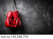 Professional red boxing gloves hang on a black background with a space to copy. Стоковое AI-изображение, AI-художник Photojuli / Фотобанк Лори