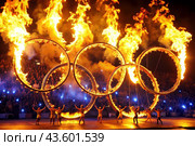 A fire show. The burning rings of the Olympic Sports Games. Стоковое AI-изображение, AI-художник Photojuli / Фотобанк Лори