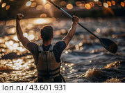A kayaker celebrates his victory with an oar in his hands on a blurred background of the river. Kayaker at the Summer Olympics. Стоковое AI-изображение, AI-художник Photojuli / Фотобанк Лори