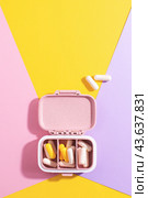 Open pill box with white and yellow capsules on colourful background. Стоковое фото, фотограф Юлия Трикашная / Фотобанк Лори