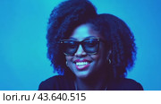 A woman wearing sunglasses and earrings is smiling in front of a blue background. Стоковое AI-видео, аниматор Юрий Поздников / Фотобанк Лори