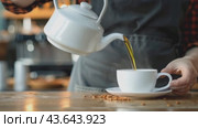 In a graceful manner, someone is pouring tea into a cup placed on a saucer, showcasing elegance. Стоковое AI-видео, аниматор Юрий Поздников / Фотобанк Лори