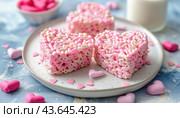 A white plate holds three pink heartshaped rice krispie treats alongside pink marshmallows. Стоковое AI-изображение, AI-художник Юрий Поздников / Фотобанк Лори