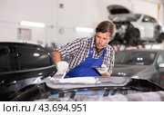Experienced auto body technician puttying damaged car bumper. Стоковое фото, фотограф Яков Филимонов / Фотобанк Лори