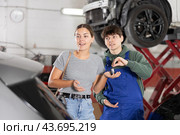 Young mechanic handing over remote key to female customer. Стоковое фото, фотограф Яков Филимонов / Фотобанк Лори
