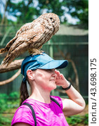 Portrait of laughing 36 years old Russian woman with Ural owl (Strix uralensis) bird sitting on her head. Стоковое фото, фотограф Татьяна Терехина / Фотобанк Лори