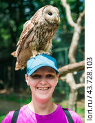 Portrait of laughing 36 years old Russian woman with Ural owl (Strix uralensis) bird sitting on her head. Стоковое фото, фотограф Татьяна Терехина / Фотобанк Лори