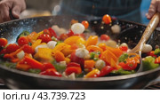 A person stirs a colorful mix of fresh vegetables in a large wok with a wooden spoon. Стоковое AI-видео, аниматор Юрий Поздников / Фотобанк Лори