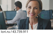 A woman is sitting in front of a computer at her workstation in a busy call center. Стоковое AI-видео, аниматор Юрий Поздников / Фотобанк Лори