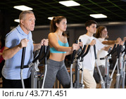 Group of people of different ages train on elliptical trainers steppers. Стоковое фото, фотограф Яков Филимонов / Фотобанк Лори