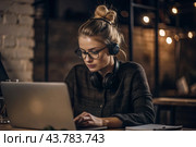 A young female freelance businessman in glasses and headphones is working on a laptop or shopping in an online store. The woman is writing something in a notebook. Стоковое AI-изображение, AI-художник Photojuli / Фотобанк Лори