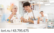 Cheerful guy working with elderly mother in family pottery studio. Стоковое фото, фотограф Яков Филимонов / Фотобанк Лори