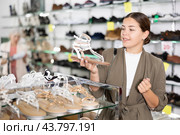 Girl client is demanding to inspect sandals in shoe showroom. Стоковое фото, фотограф Яков Филимонов / Фотобанк Лори