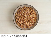 Boiled buckwheat porridge in black bowl on wooden background, top view. Стоковое фото, фотограф Natalia Gdovskaia / Фотобанк Лори